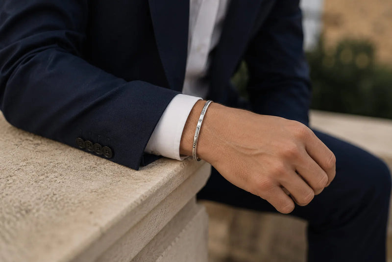 Close-up of a navy wedding guest suit styled with a crisp white shirt and slim silver bracelet