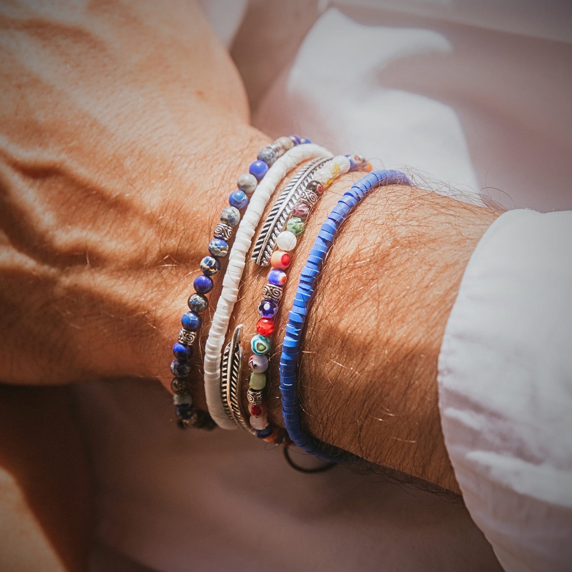Close-up wrist with off white bracelet and other stacked pieces