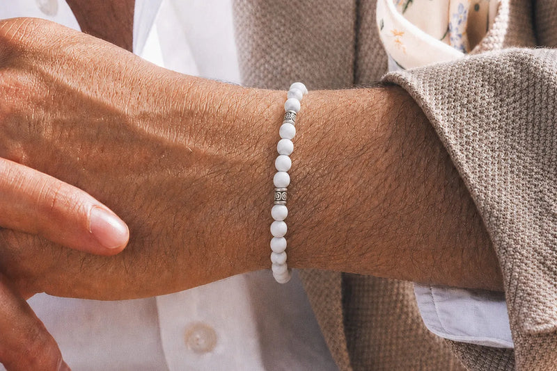 Men's white beaded bracelet worn with a beige jacket and white shirt for a clean neutral look