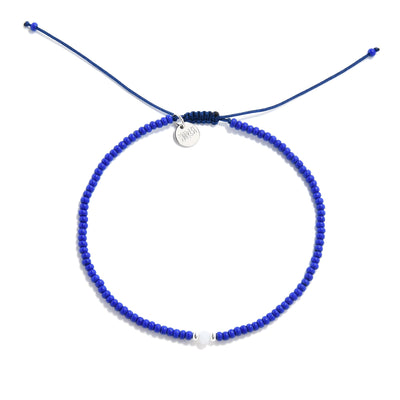 Flat lay of minimalist seed bead bracelet in blue with center white and silver accent