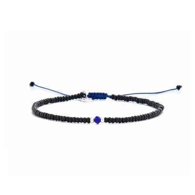 Minimalist bead bracelet with black beads, white spacers, and blue center on navy cord