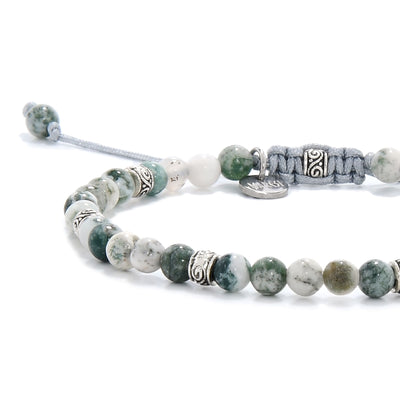 Close-up view of a moss agate bracelet showing green and white marbled beads with metal accents and a light blue adjustable cord.