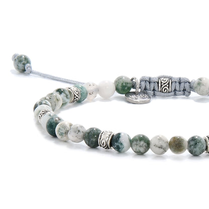 Close-up view of a moss agate bracelet showing green and white marbled beads with metal accents and a light blue adjustable cord.