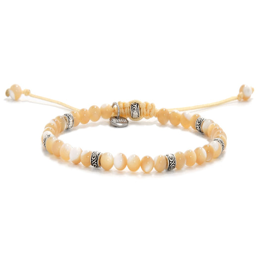 Close-up view of a mother of pearl bracelet with creamy yellow and white beads, featuring metal spacers and an adjustable yellow cord
