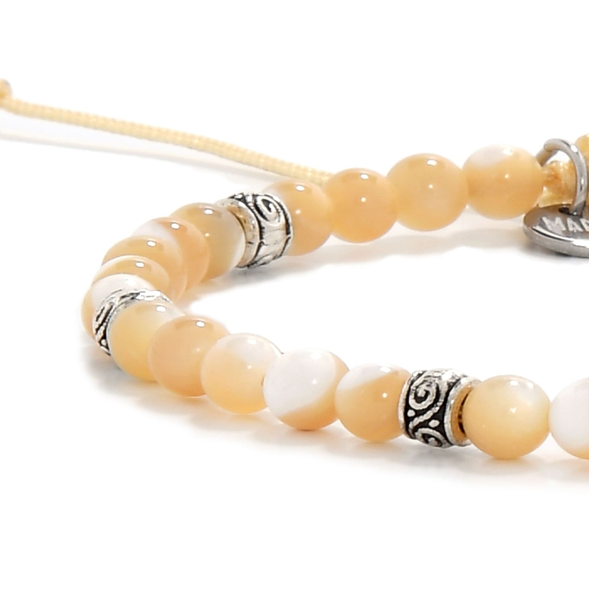 Zoomed-in detail of the bracelet showing lustrous mother of pearl beads and decorative silver spacers on a light background.