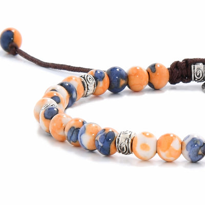 Close-up of orange stone bracelet showing patterned silver spacers and colorful beads.