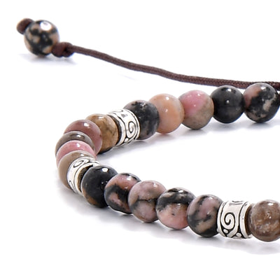 Zoomed-in section of a rhodonite bracelet showing the blend of pink, earthy hues, and metallic spacer details on a dark brown cord.