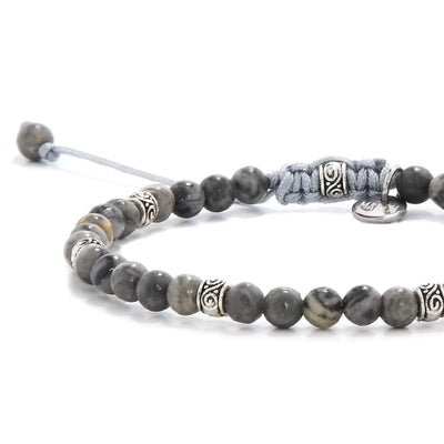 Close-up of polished gray stone beads with silver accent spacers.