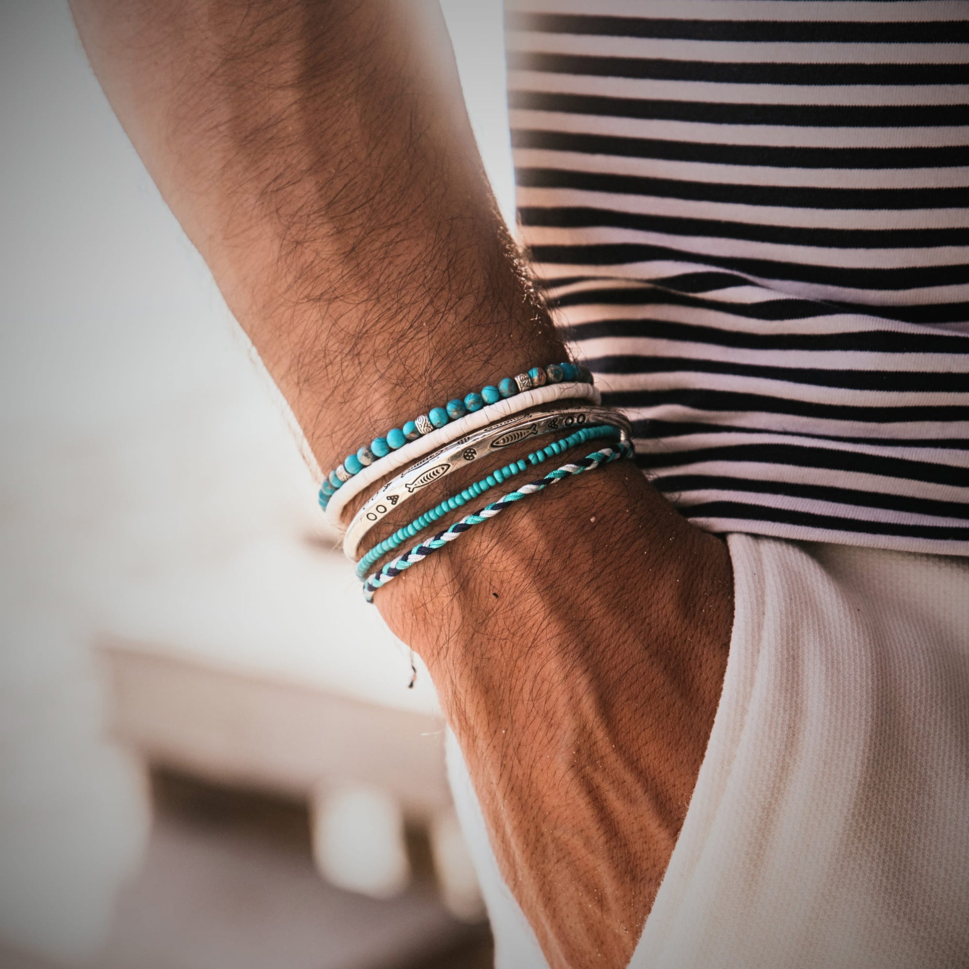  Close-up of a man's wrist wearing the Positano bracelet set, featuring silver and turquoise stacking bracelets.