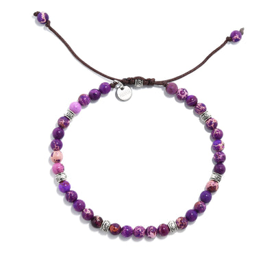 Overhead view of a purple jasper stone bracelet with silver accents on brown cord.