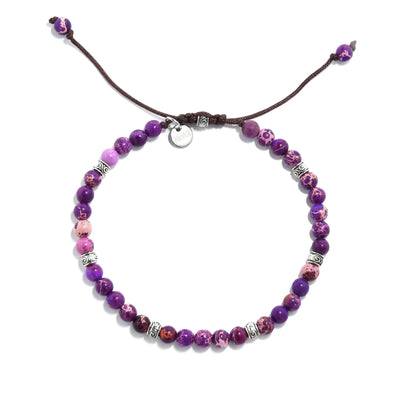Overhead view of a purple jasper stone bracelet with silver accents on brown cord.
