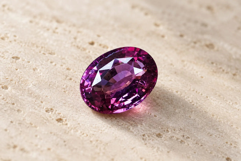 Faceted purple spinel gemstone with rich violet and magenta tones in an oval cut