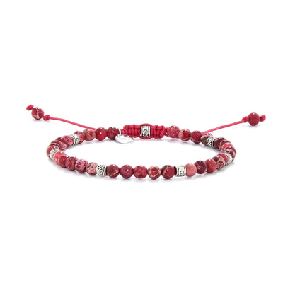 Handmade red jasper bracelet featuring round beads and silver spacers on red cord.
