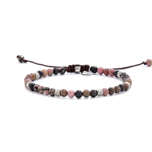 Close-up view of a rhodonite crystal bracelet featuring pink and black marbled beads, accented with ornate metal spacers and a brown adjustable cord.