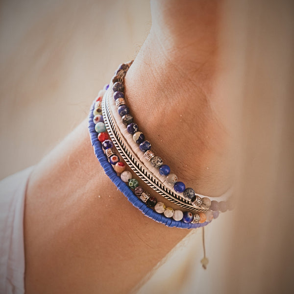 Close-up of a wrist wearing the Santorini bracelet set, featuring stacked colorful beaded bracelets with blue, white, and silver accents.