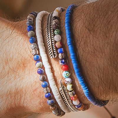  Zoomed-in shot of the Santorini bracelet set highlighting the mix of blue, white, and multicolor beads along with a silver feather-style bracelet.