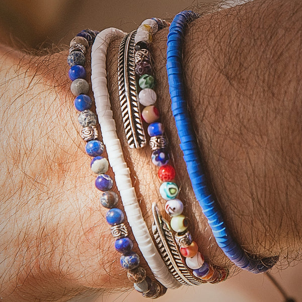  Zoomed-in shot of the Santorini bracelet set highlighting the mix of blue, white, and multicolor beads along with a silver feather-style bracelet.