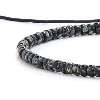Close-up of black seed bead bracelet with speckled glass beads and black cord