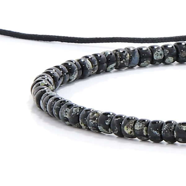 Close-up of black seed bead bracelet with speckled glass beads and black cord