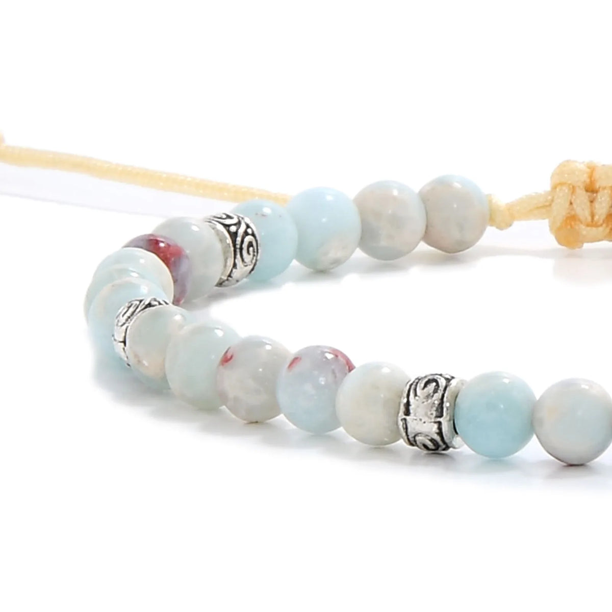 Close-up of a Shoushan stone bracelet featuring smooth round beads in soft blue and white tones with red accents, paired with detailed metal spacers and a beige cord.