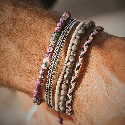 Purple jasper bracelet stacked with braided and silver bangles on wrist.
