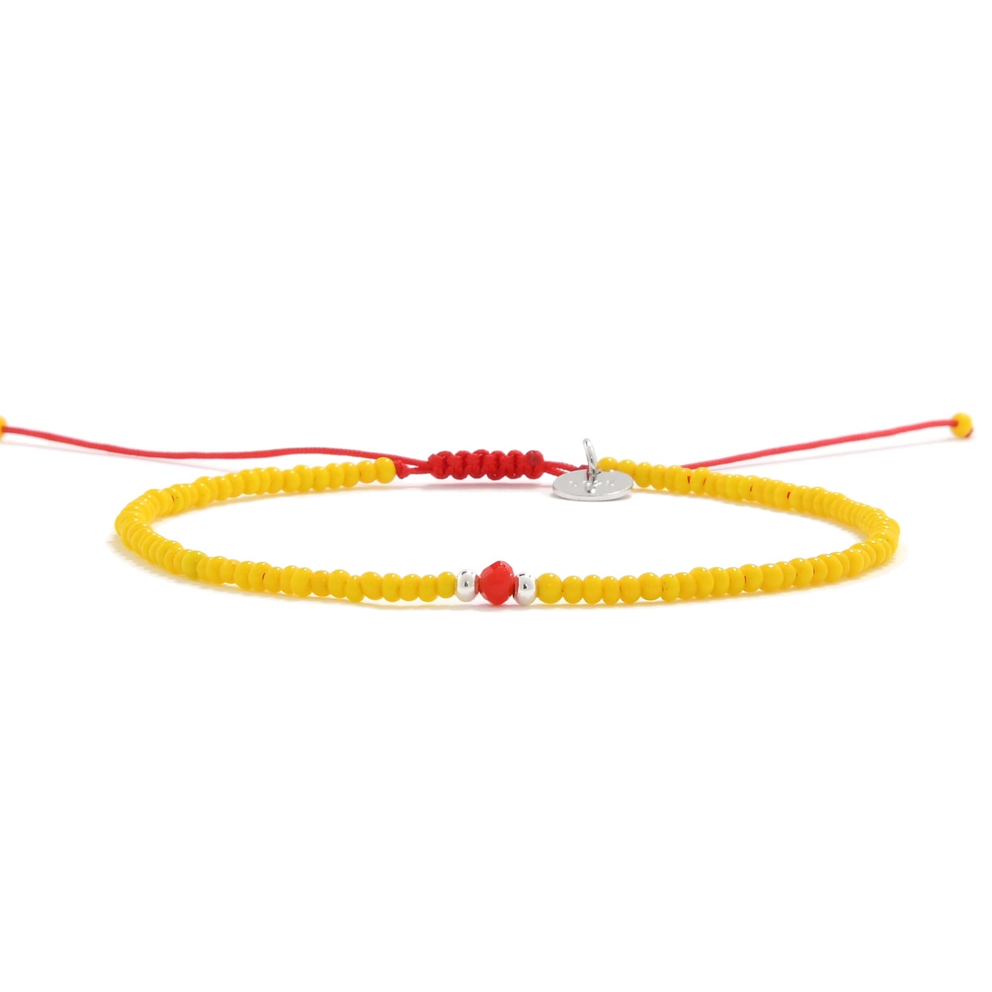 Yellow bracelet with center red glass bead on red string