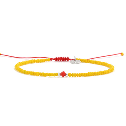 Yellow bracelet with center red glass bead on red string