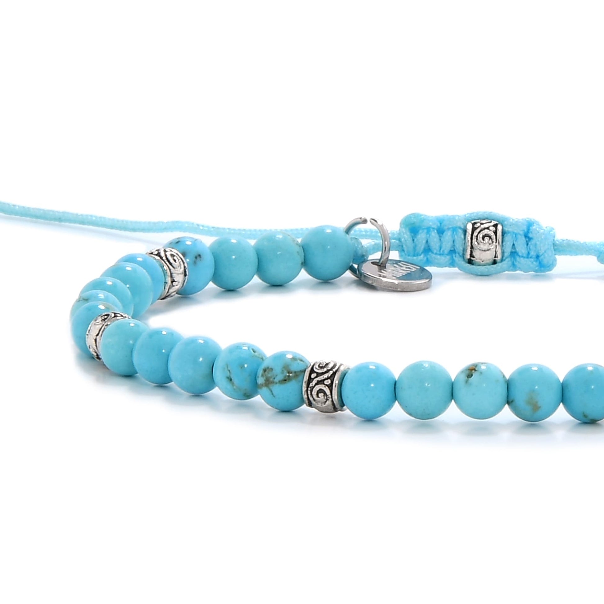 Close-up of turquoise bracelet showing detailed silver beadwork and blue thread clasp