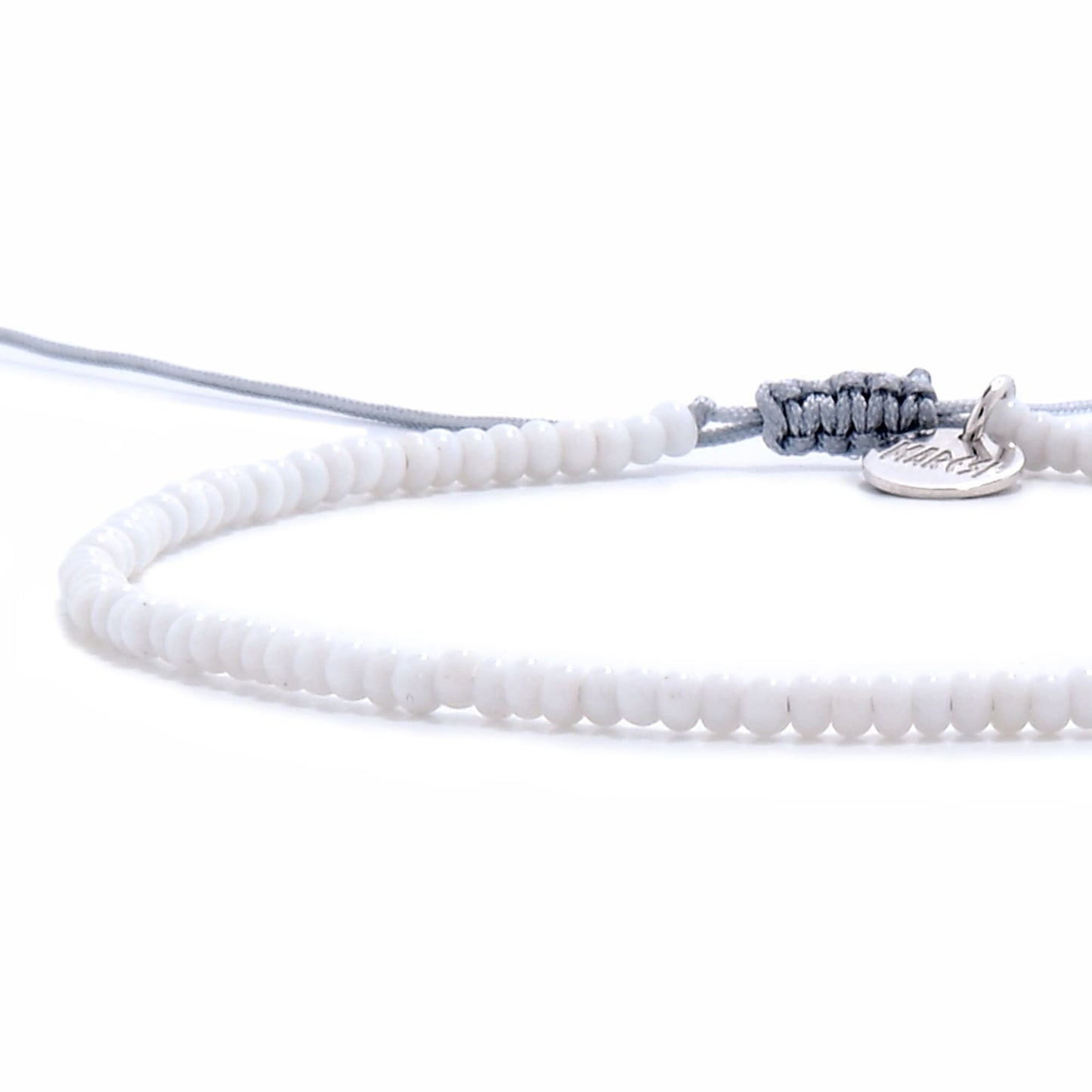 mall beaded bracelet in white seed beads shown from an angled perspective with soft gray cord