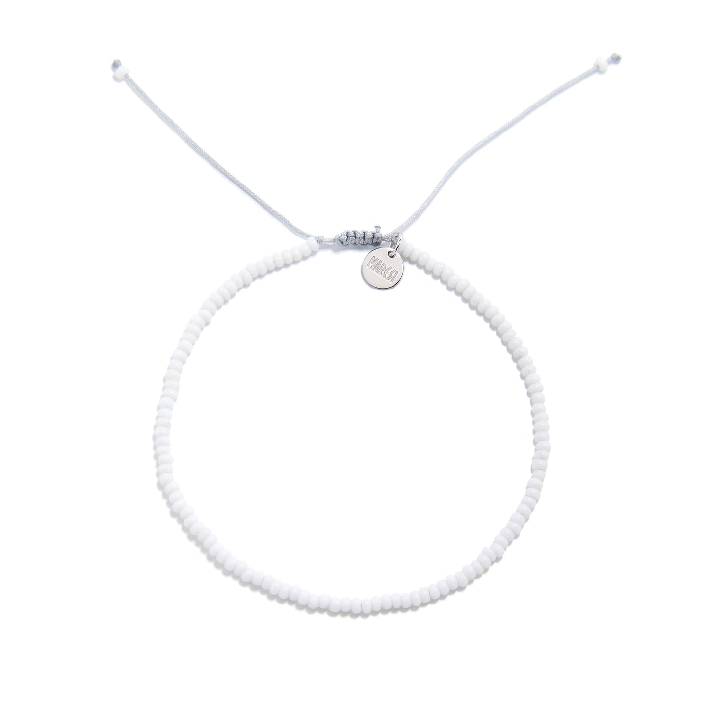 Overhead view of small beaded bracelet in white with fine seed beads and silver logo charm