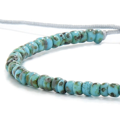 Detailed view of Bead Bracelet with turquoise Picasso seed beads with gray cord, Picasso seed bead texture, and cord knot