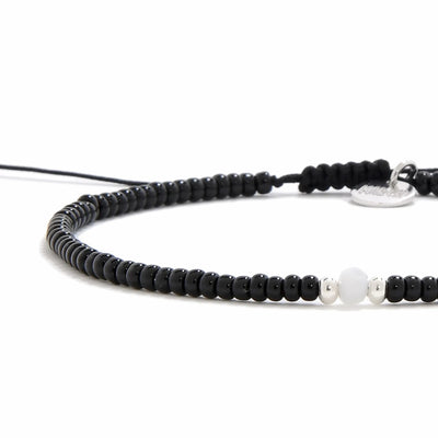 Close-up of Bead Bracelet Black showing black seed beads with white accent beads, silver charm, and cord closure