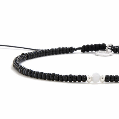 Close-up of Bead Bracelet Black showing black seed beads with white accent beads, silver charm, and cord closure