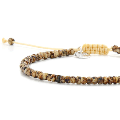 Close-up of Bead Bracelets for Men showing brown Picasso seed beads with cream cord, silver charm, and cord closure