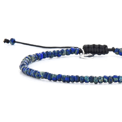 Close-up of Beaded Bracelets for Men showing blue Picasso seed beads with black cord, silver charm, and cord closure