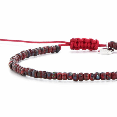Close-up of Beads Bracelets showing red Picasso seed beads with red cord, silver charm, and cord closure