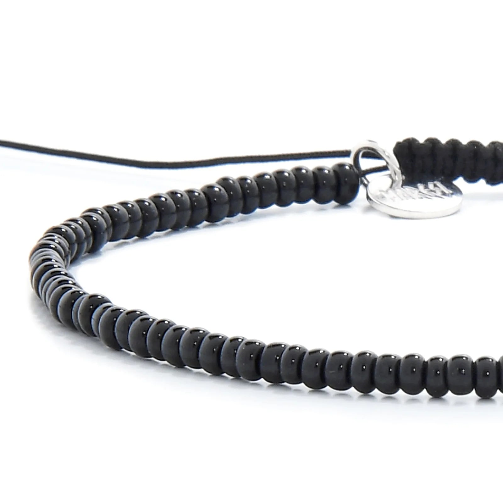 Detailed view of Black Bead Bracelet with black seed beads with silver charm, seed bead texture, and cord knot