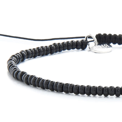 Detailed view of Black Bead Bracelet with black seed beads with silver charm, seed bead texture, and cord knot