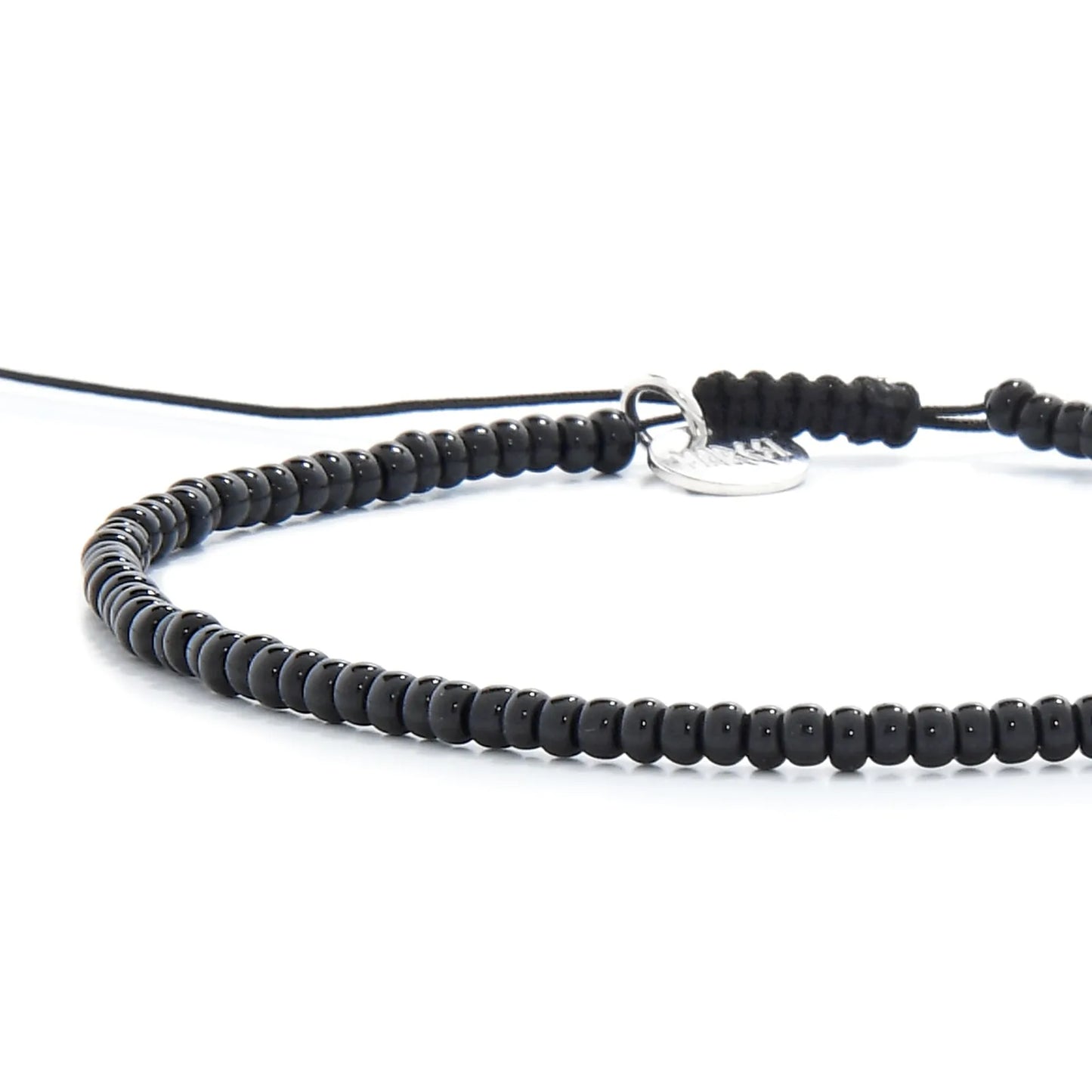 Close-up of Black Bead Bracelet showing black seed beads with silver charm, silver charm, and cord closure