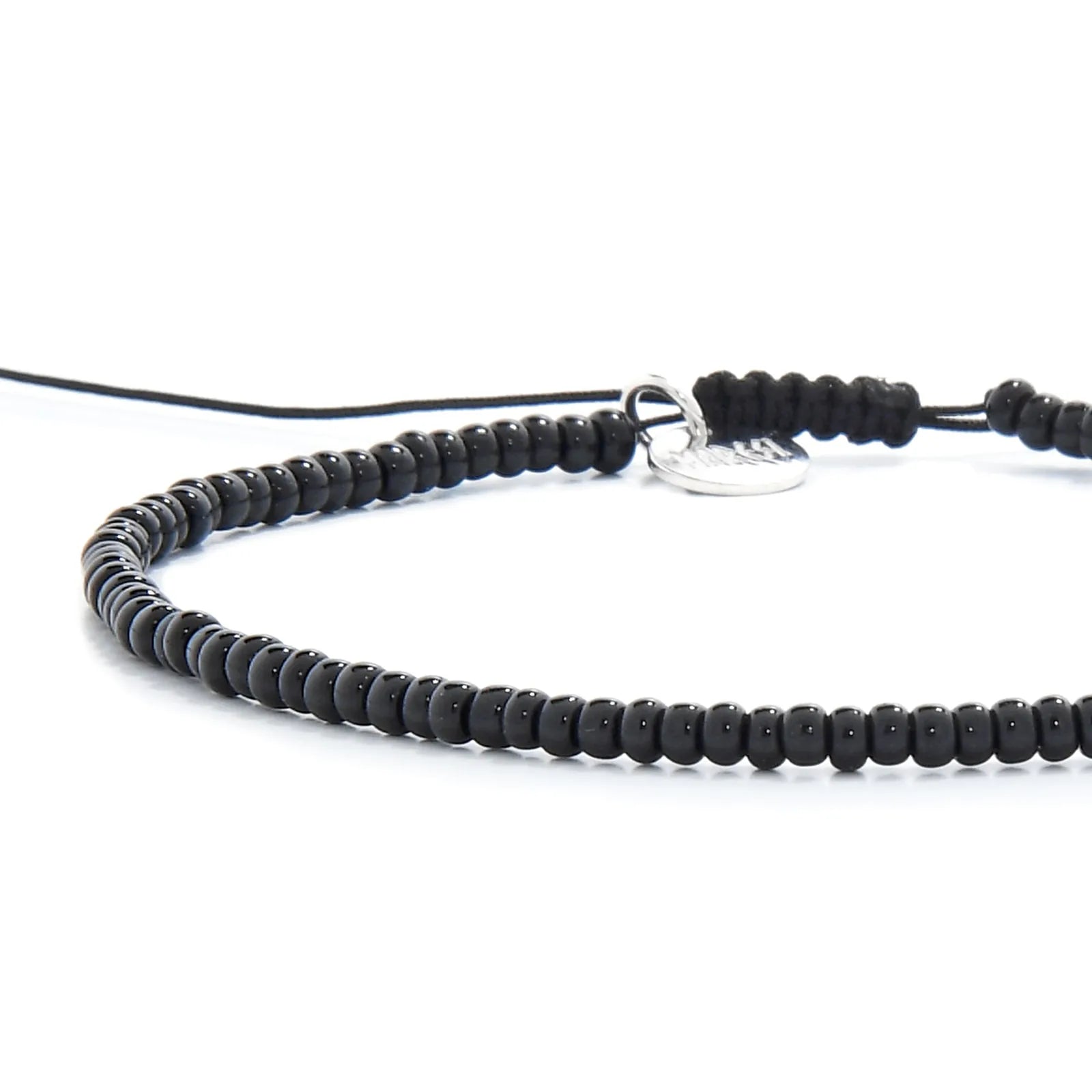Close-up of Black Bead Bracelet showing black seed beads with silver charm, silver charm, and cord closure