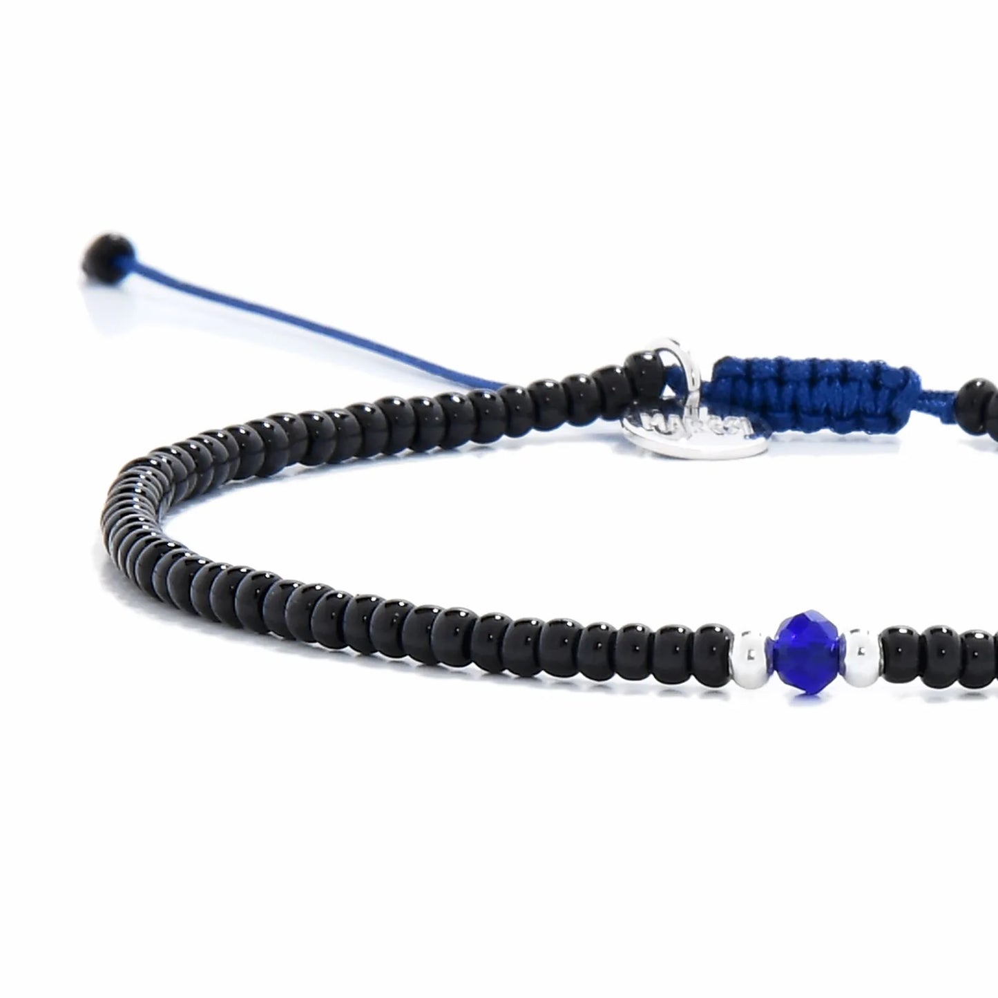 Close-up of black and blue bead bracelet showing black seed beads with blue accent beads, silver charm, and cord closure