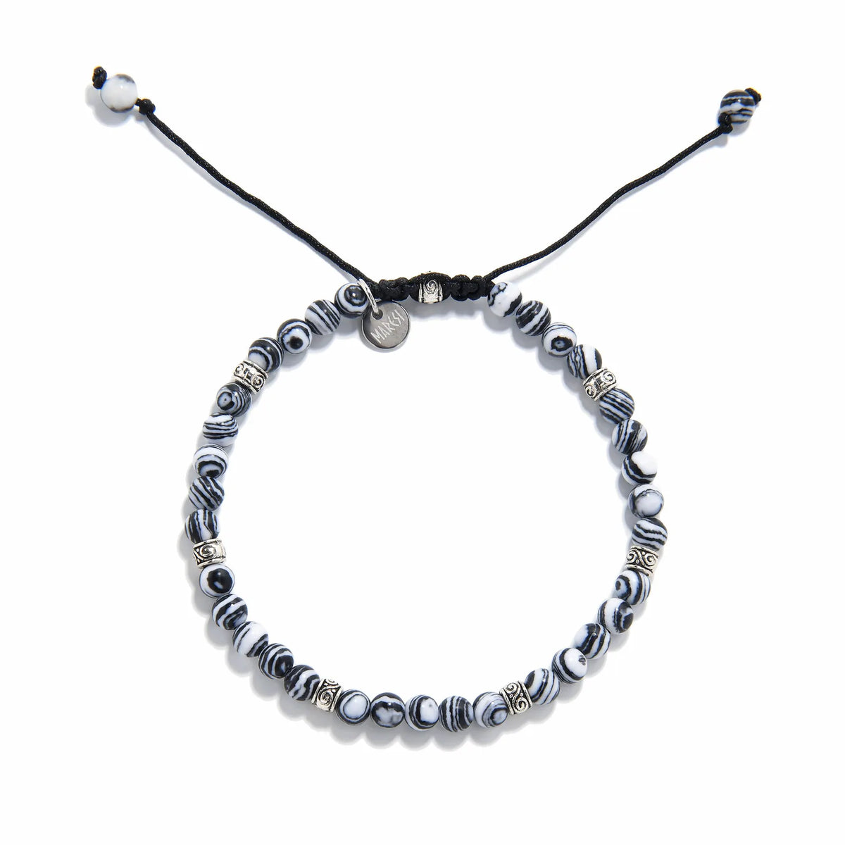 black and white beaded bracelet laid flat, showing circular pattern and woven cord clasp