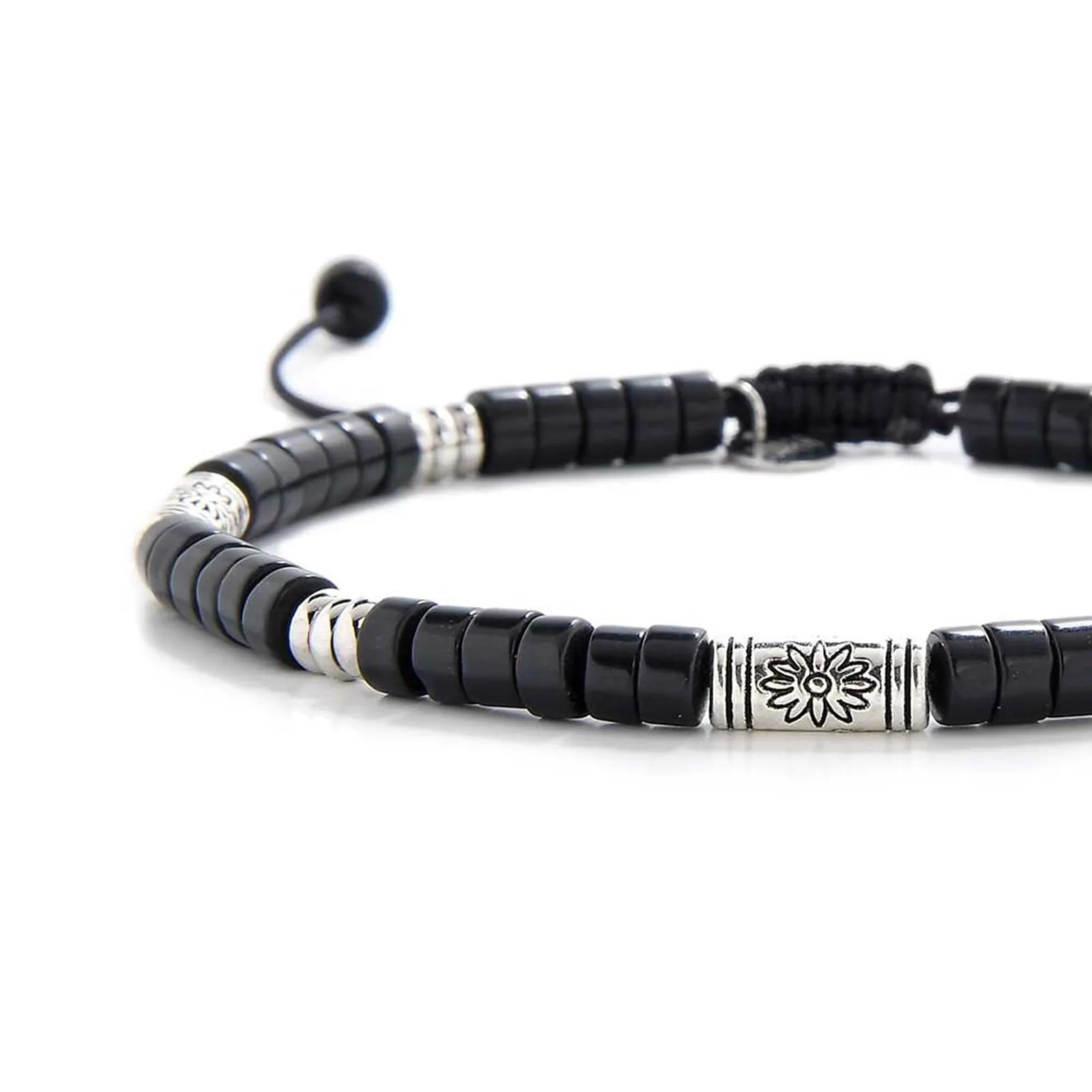 Close-up of black shamballa bracelet showing black clay beads with engraved silver spacers, silver charm, and cord closure