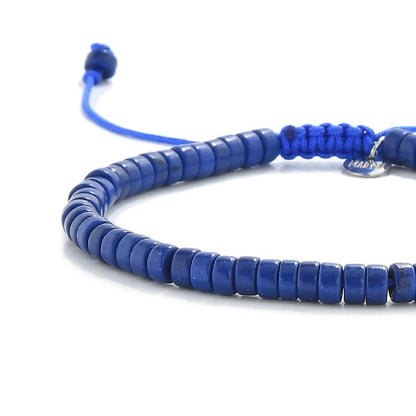 Close-up of Blue Stone Bracelet showing blue clay beads with silver charm, silver charm, and cord closure