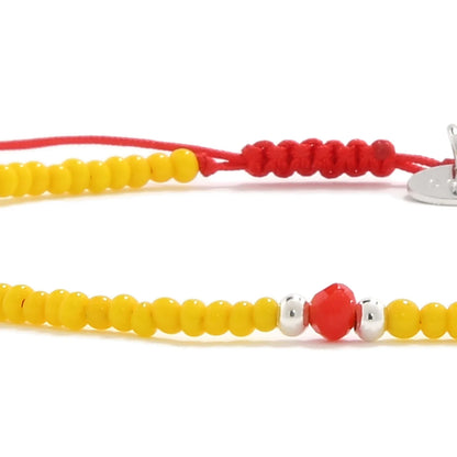 Detailed view of Bracelet with Glass Beads with yellow seed beads with red glass accents, seed bead texture, and cord knot