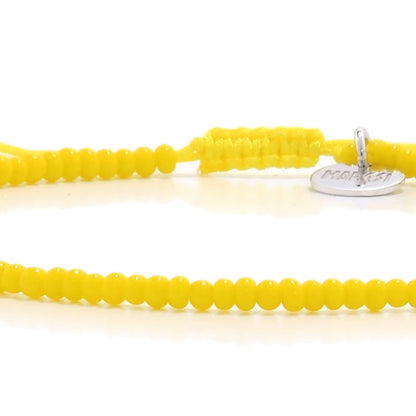 Detailed view of Bracelets Beads Essential with yellow seed beads with silver charm, seed bead texture, and cord knot