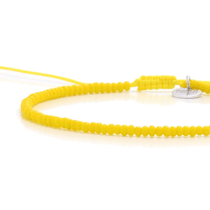 Close-up of Bracelets Beads Essential showing yellow seed beads with silver charm, silver charm, and cord closure