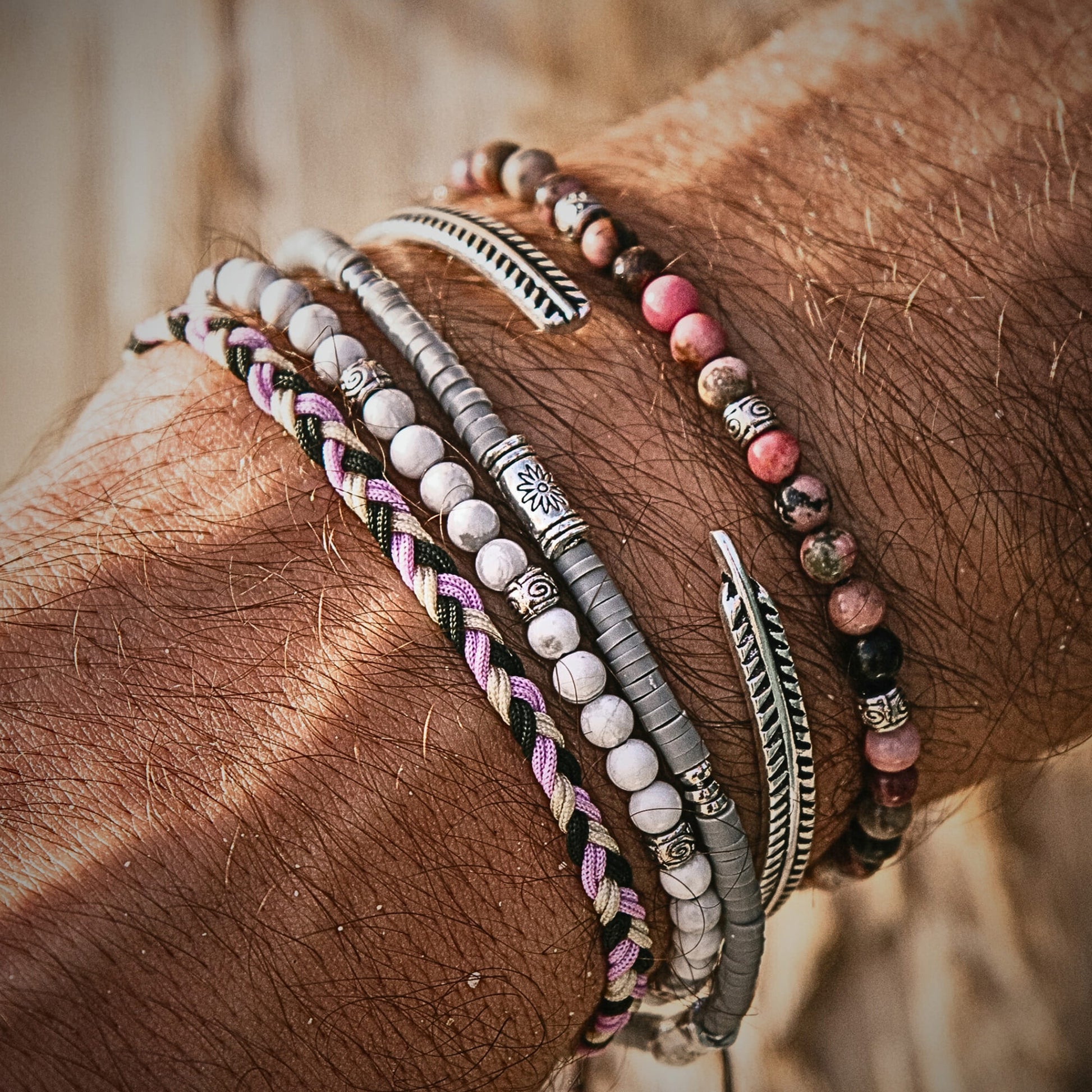 Close-up of stacked bracelets featuring gray shamballa bracelet with engraved details