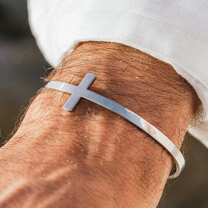 Lifestyle wrist view of cross bracelet with silver tone cuff and raised cross centerpiece