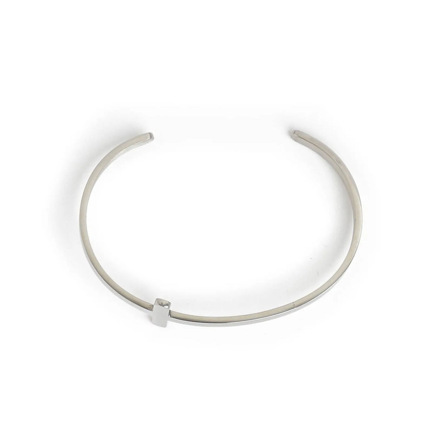Cross bracelet shown from above with open cuff shape and raised cross centerpiece